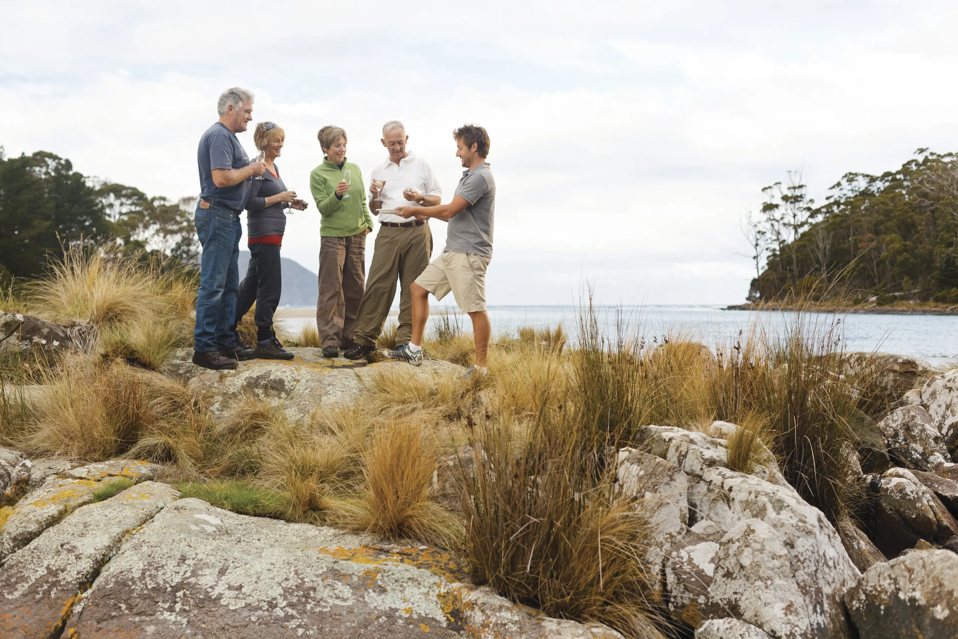 A group of friends cheers their glasses outside at Cloudy Bay Lagoon accomodation, Bruny Island