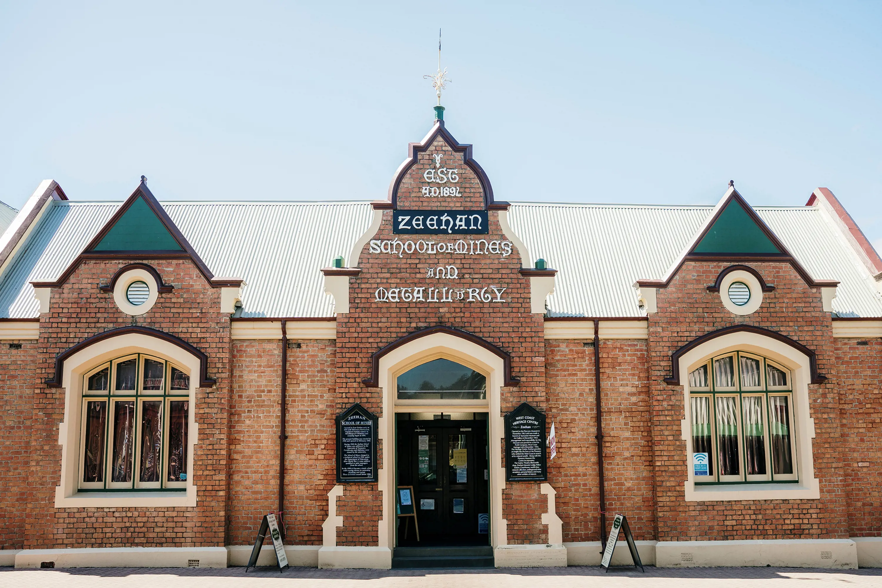 A late 19th century brick building with elaborate spires and a sign written in calligraphy. 