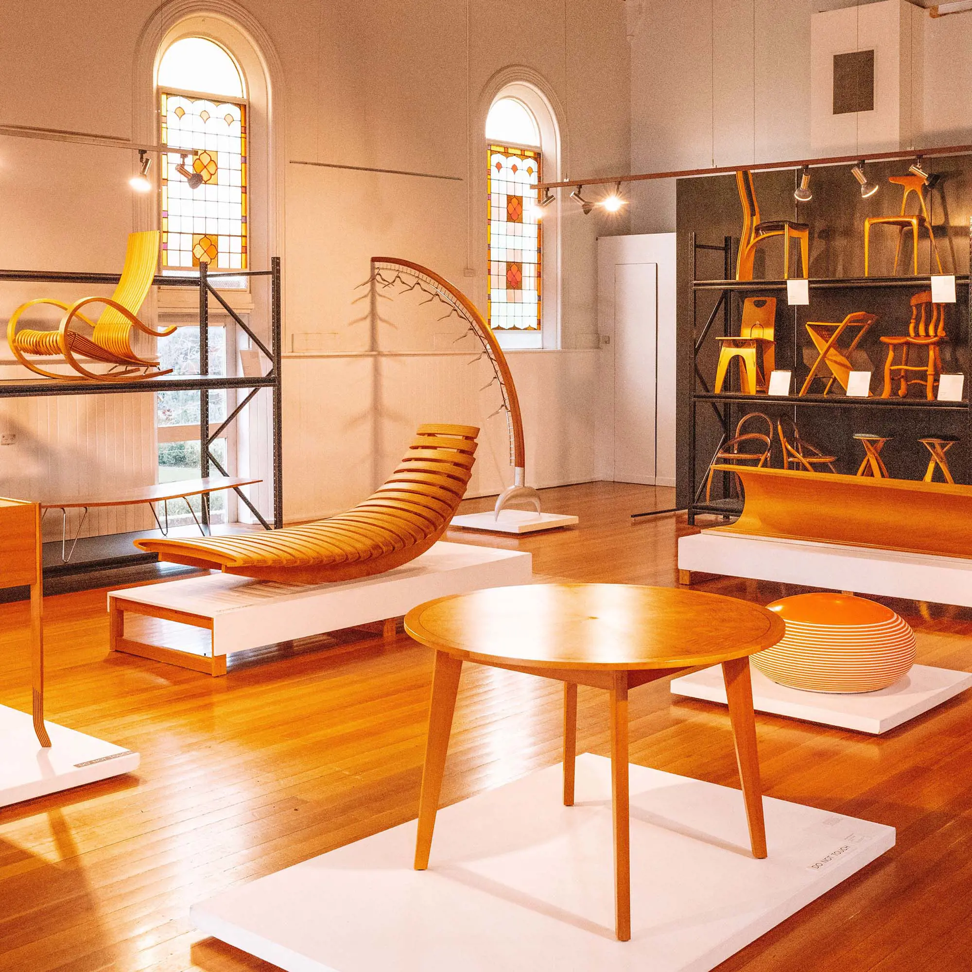 The interior of a furniture design studio, with many pieces of timber furniture displayed on shelves and pedestals.