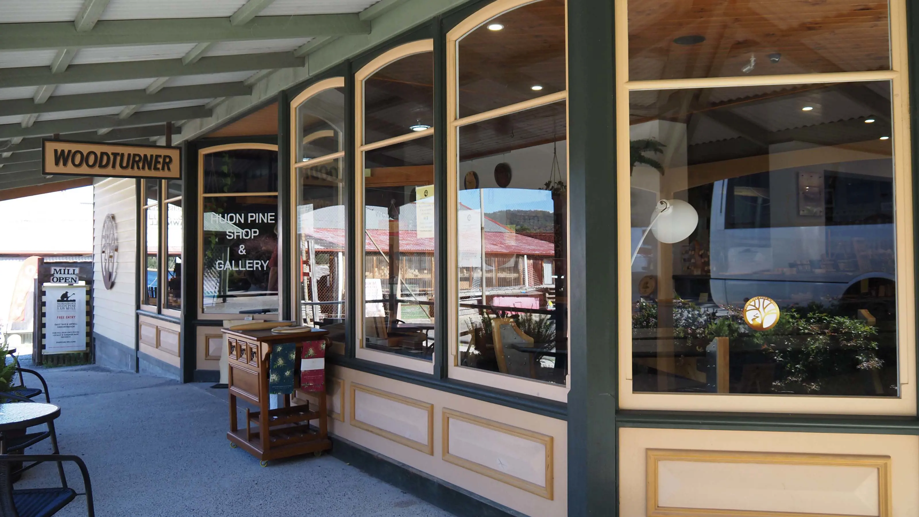 A colonial style shop front with large windows for displays and a verandah. A large sign is hung above the entrance and reads woodturner.