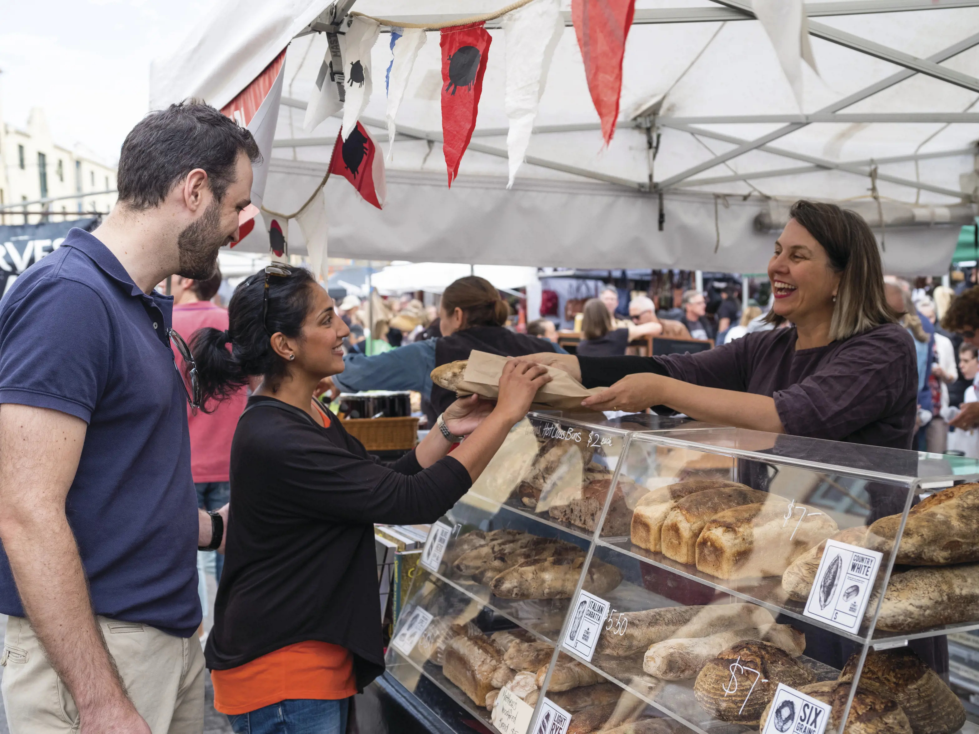 Couple purchasing bread from a stall at Salamanca Market. The market is set among historic Georgian sandstone buildings at Salamanca Place, Hobart.
