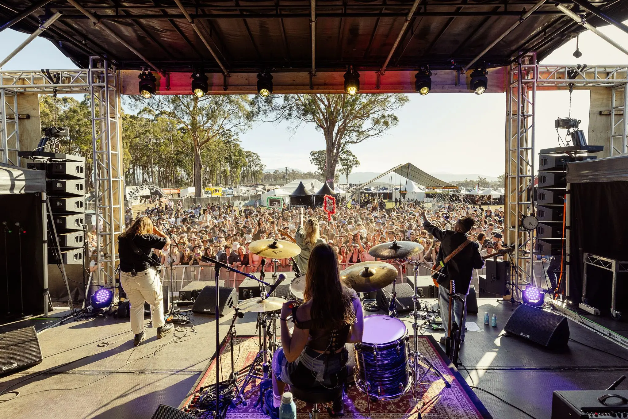 At the back of a festival stage looking out over the band and the crowd beyond.