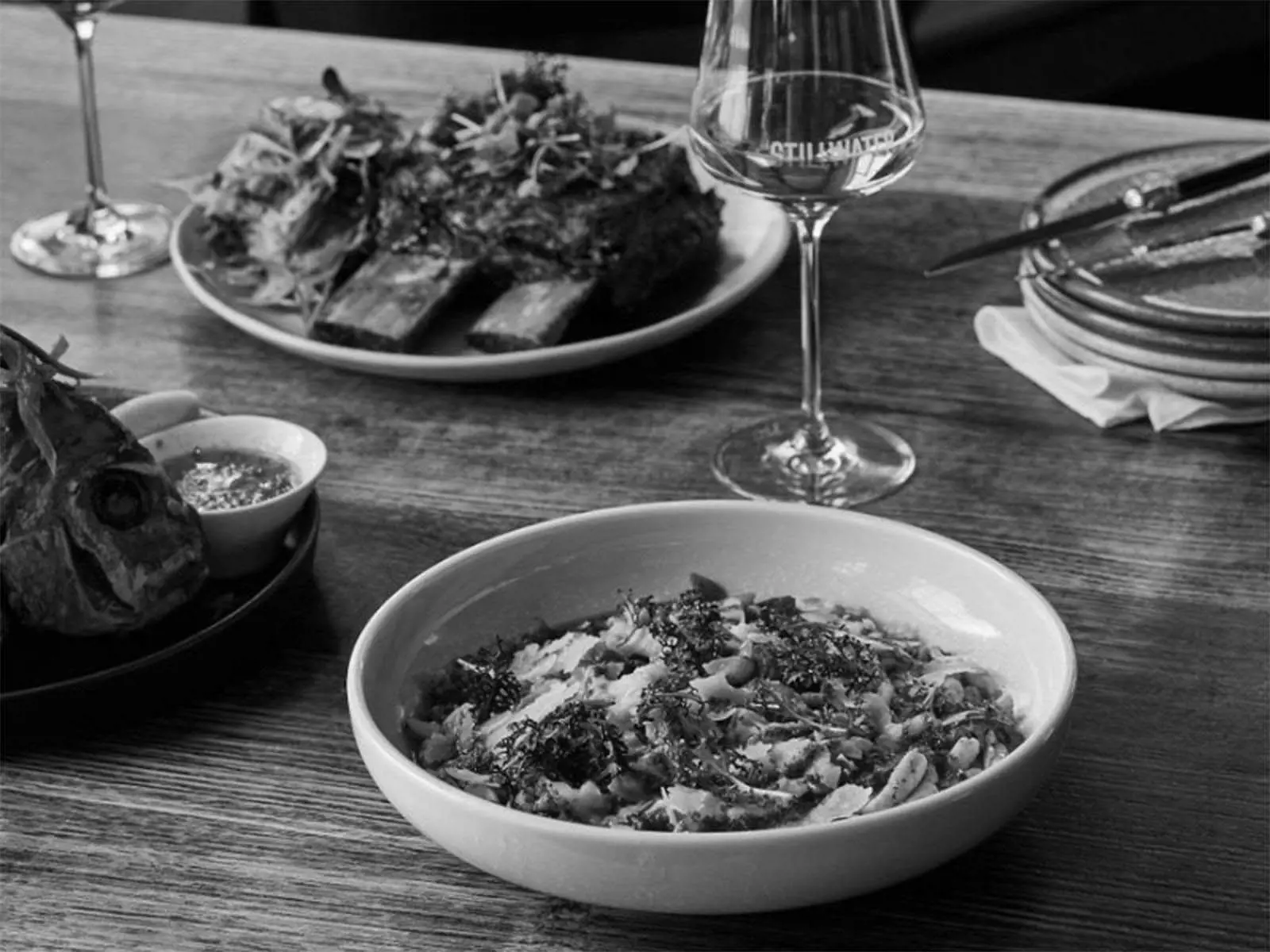 A table set with plates of delicious pasta and other meals, accompanied by elegant glasses of white wine.