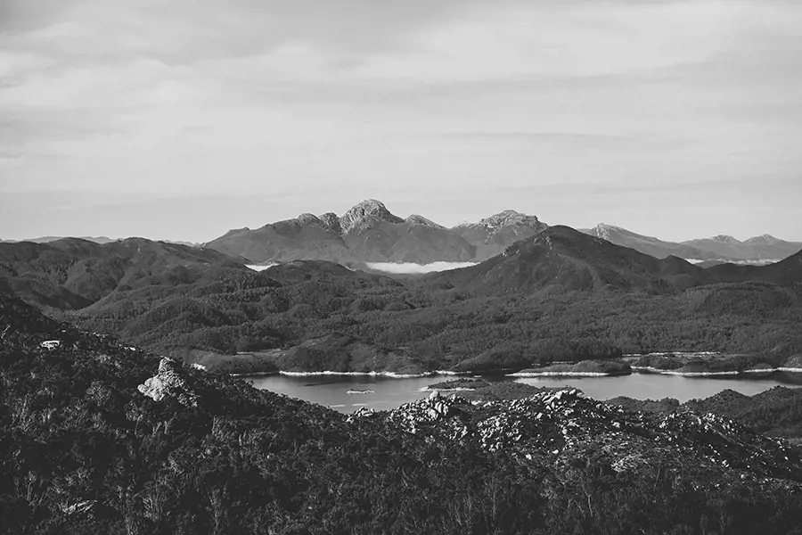 Frenchmans Cap rises sharply in the distance, dusted with snow, mirrored by the still, icy waters of Lake Burbury.