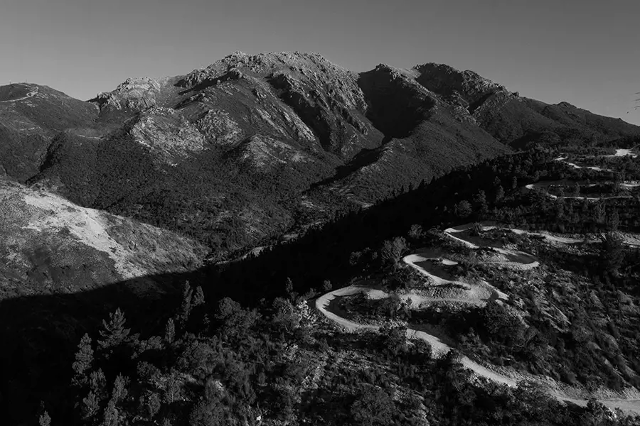 A mountain biker rides across the raw, rocky slopes of Mount Owen under heavy winter skies.