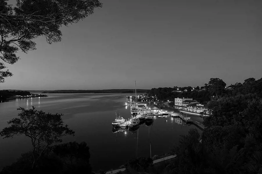 Fishing boats bob at the dock in Strahan village, with cosy winter light reflecting off the water.