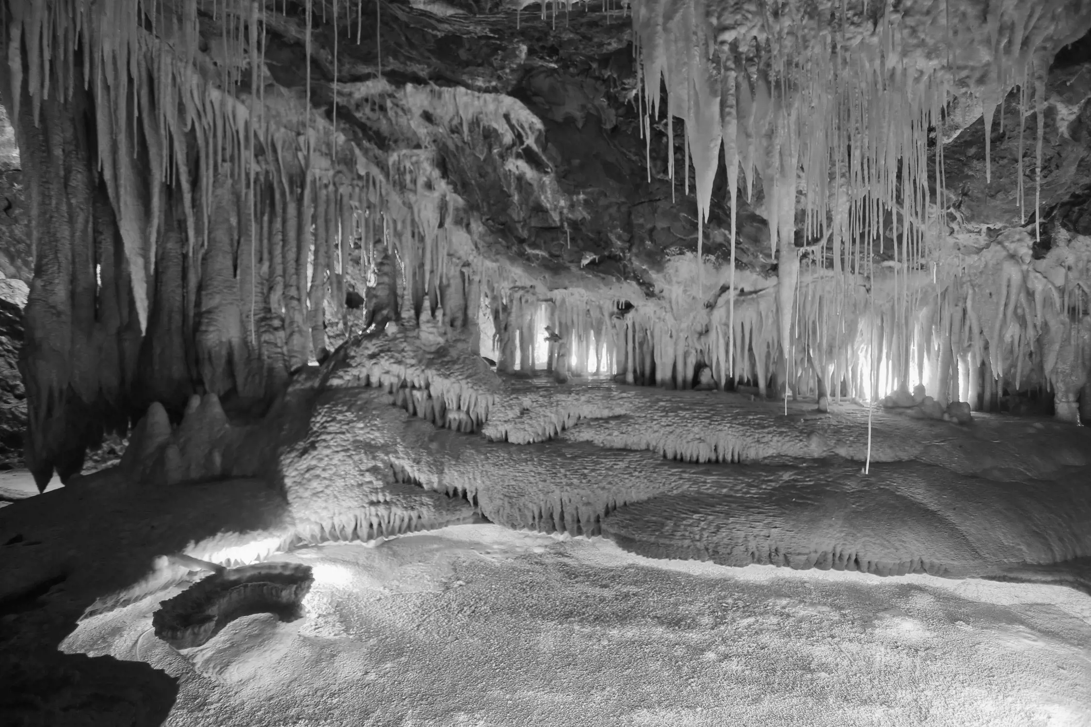 The interior of an underground cave, with undulating waves of rock and crystal formations.