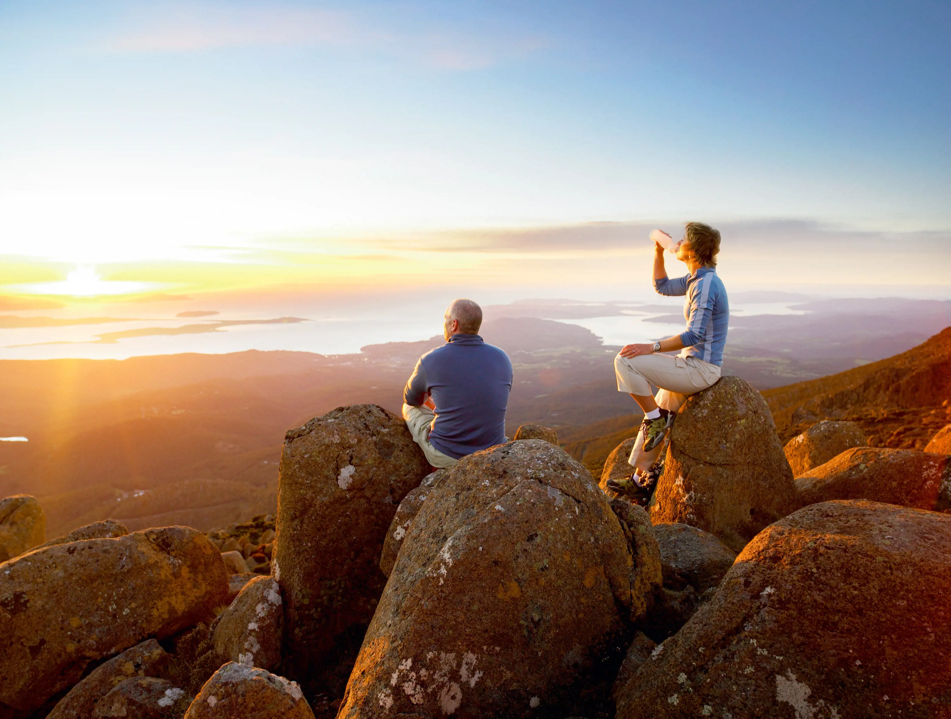 Couple at the top of the peak, looking over Hobart from Kunanyi / Mt Wellington during an incredible sunrise.