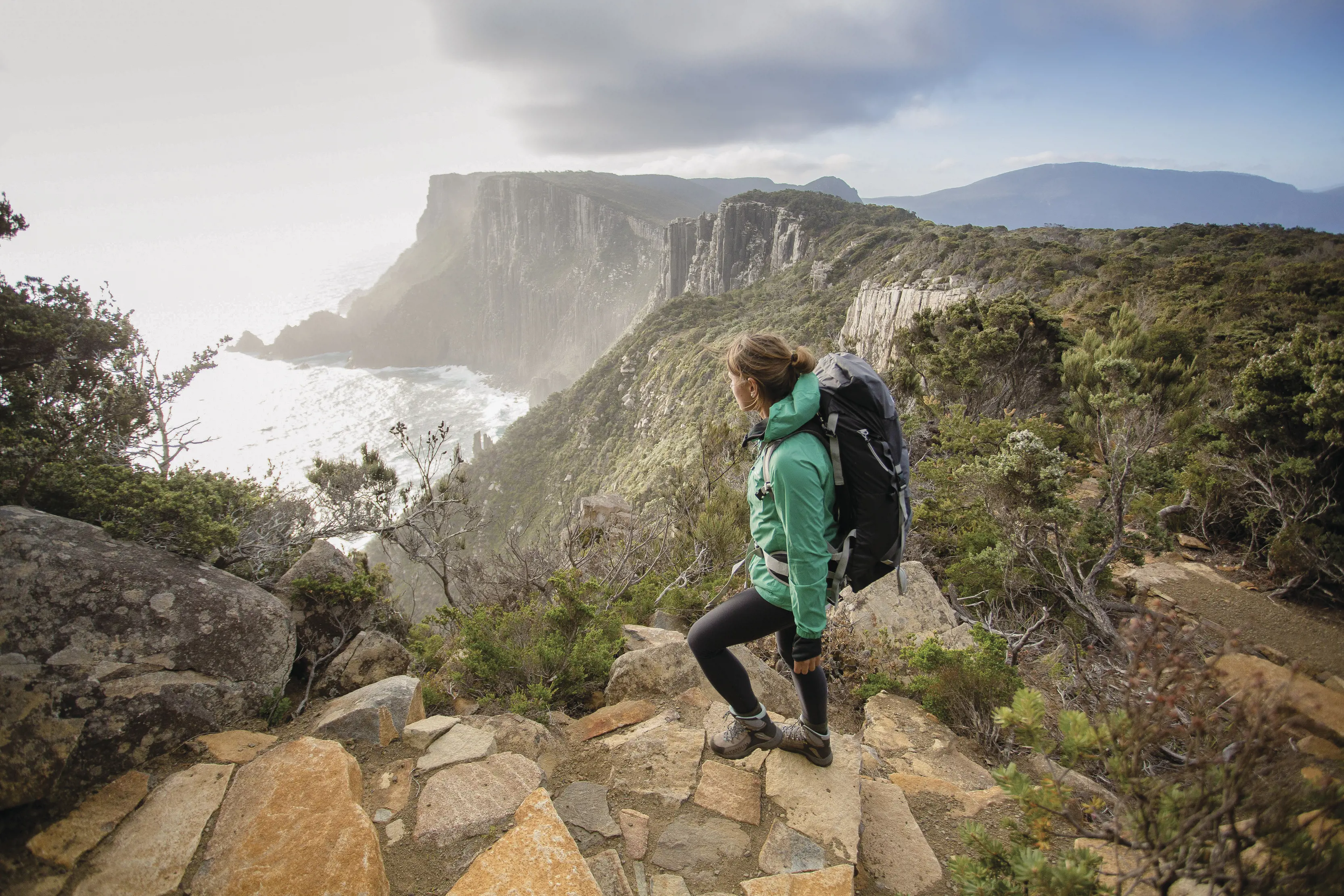 A hiker looks out at Cape Pillar and the Blade from The Three Capes Track, Tasman National Park