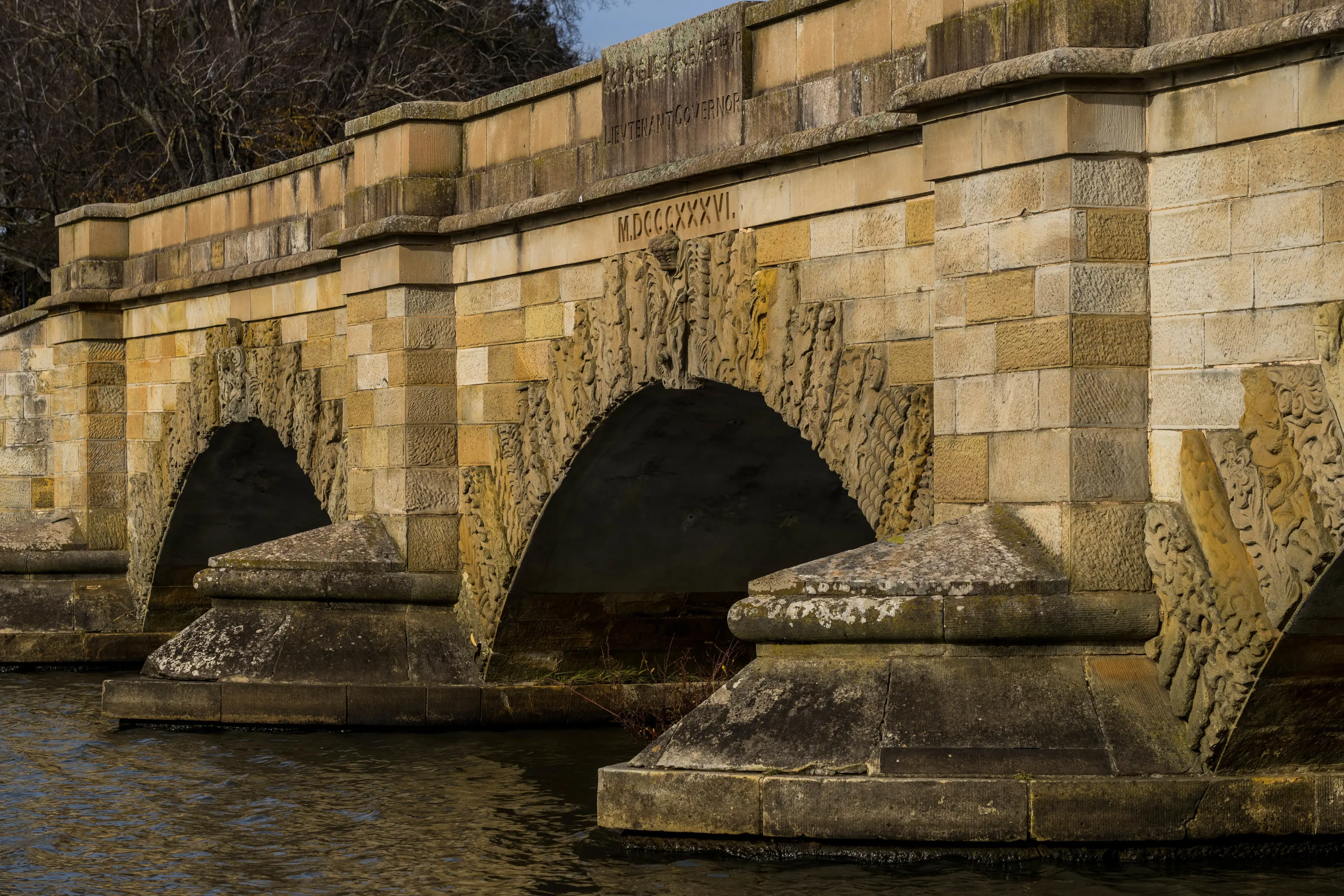 Close up image of the charming sandstone Ross Bridge and surrounding water.