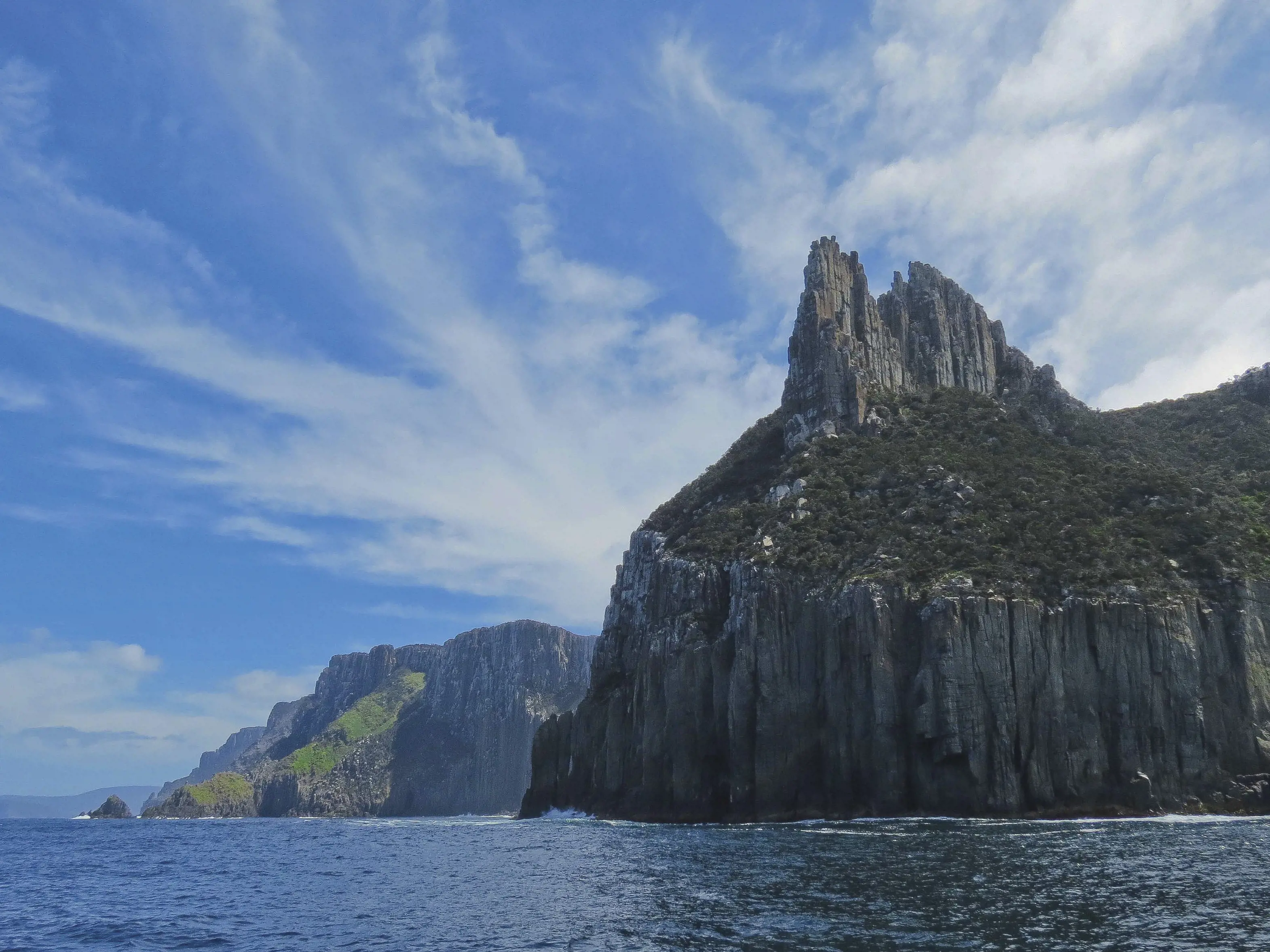 Incredible view of Cape Pillar and The Blade from the ocean with Tasman Island Cruise. Large cliff faces surrounded by deep blue ocean.