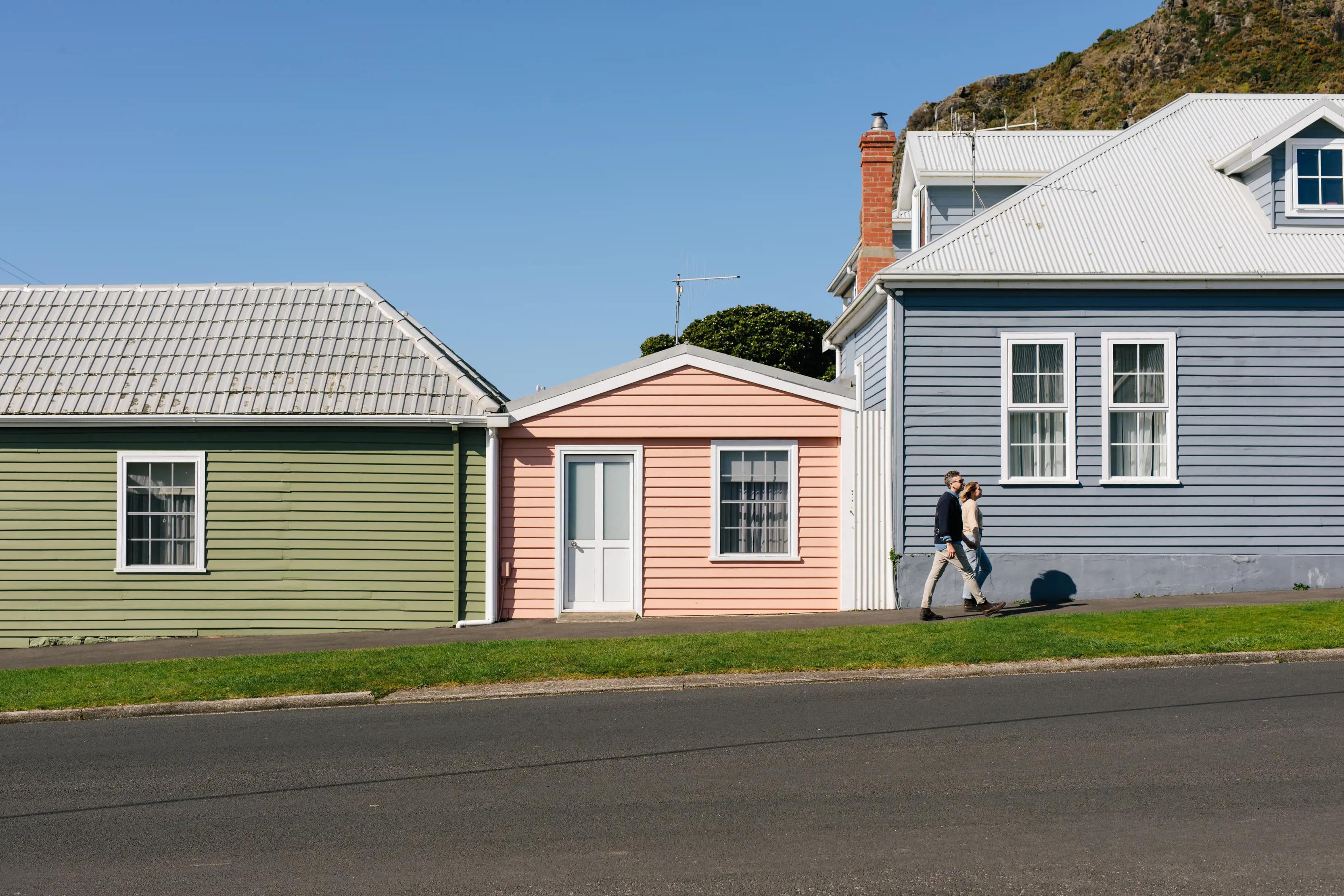 Image of a couple walking past three vibrant coloured cottages.