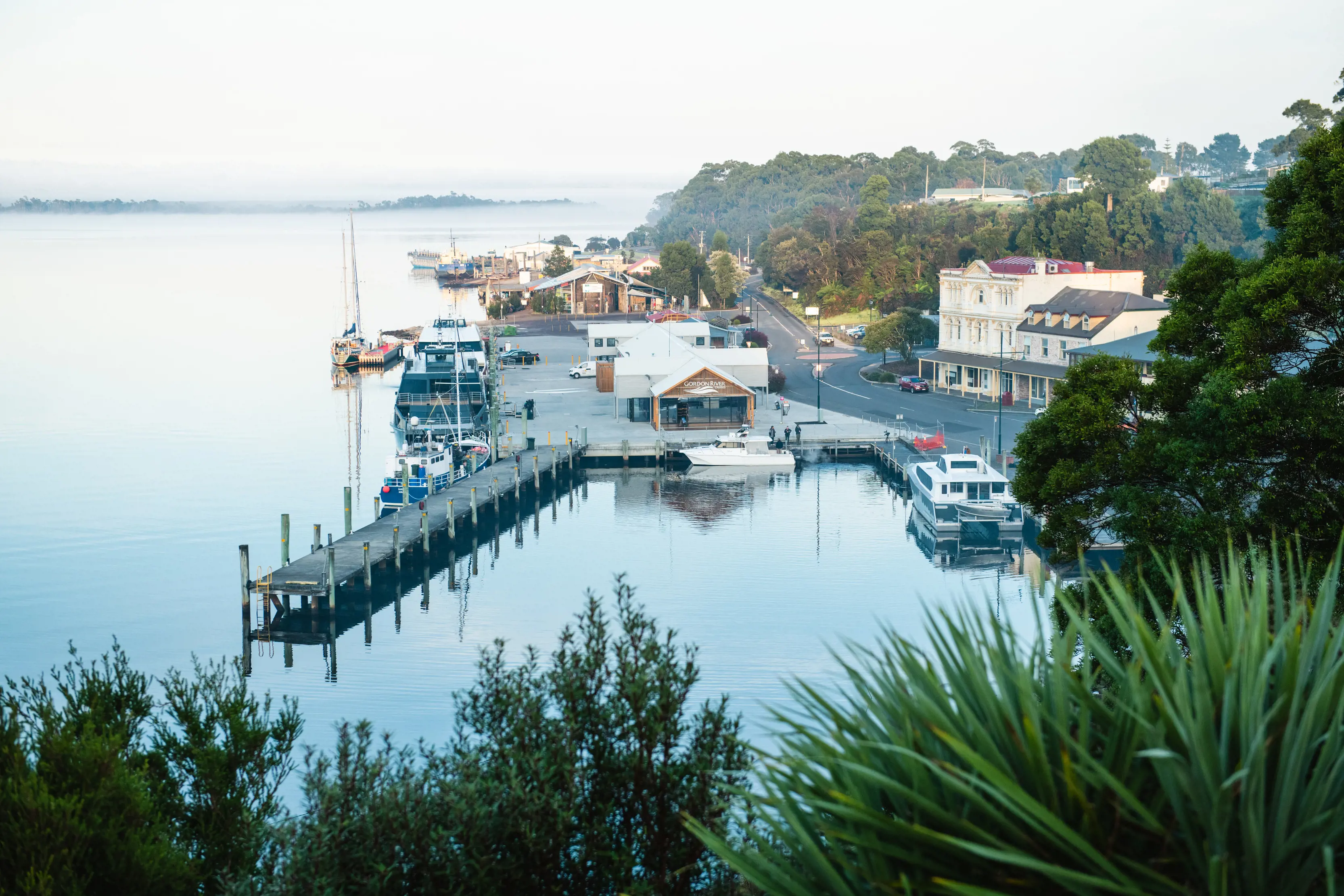 Stunning shot of Strahan waterfront with the completely still water reflecting the jetty off its surface.