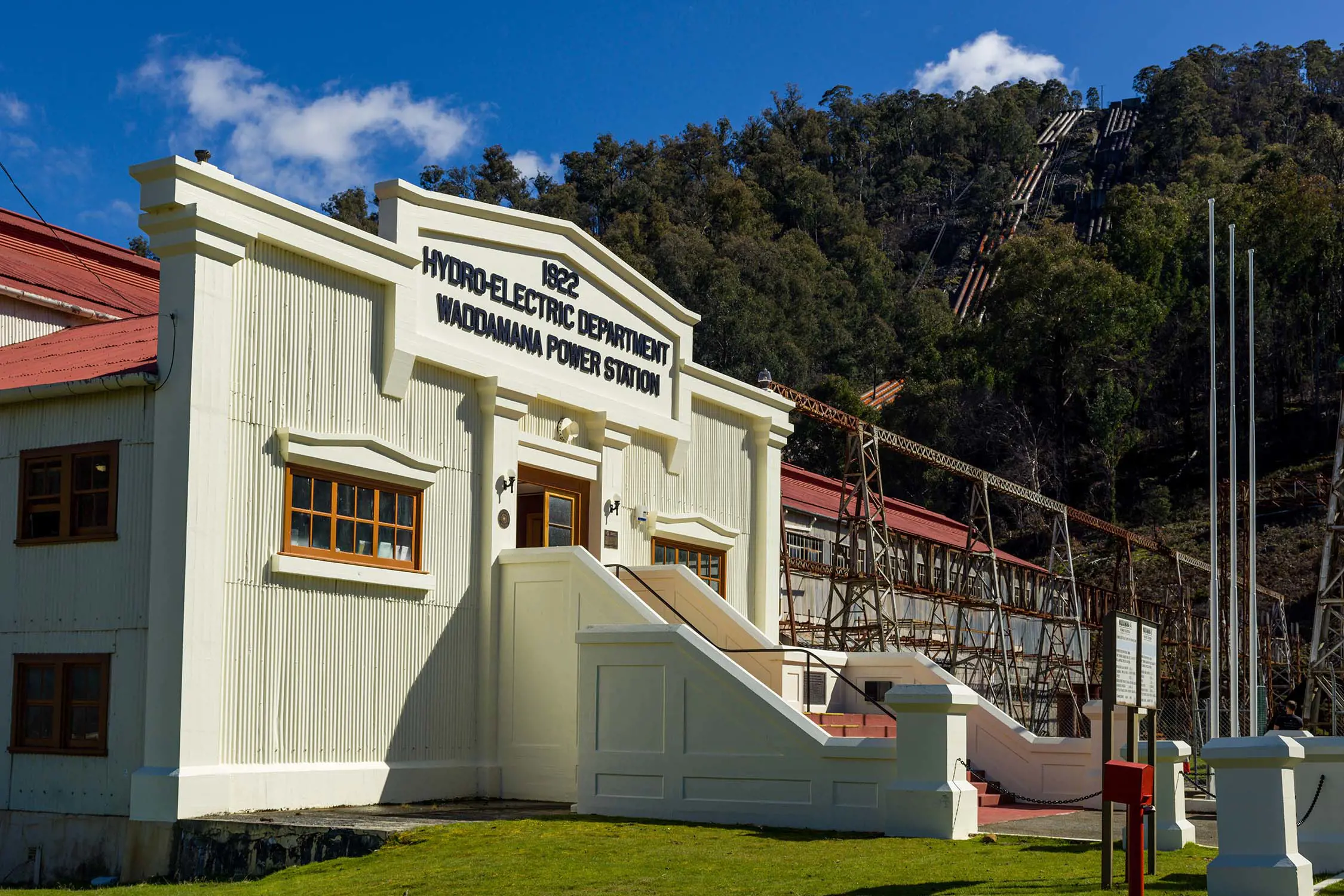 Sun shining over the entrance to the Waddamana Power Station Historic Site with the penstocks on the hill in the background.